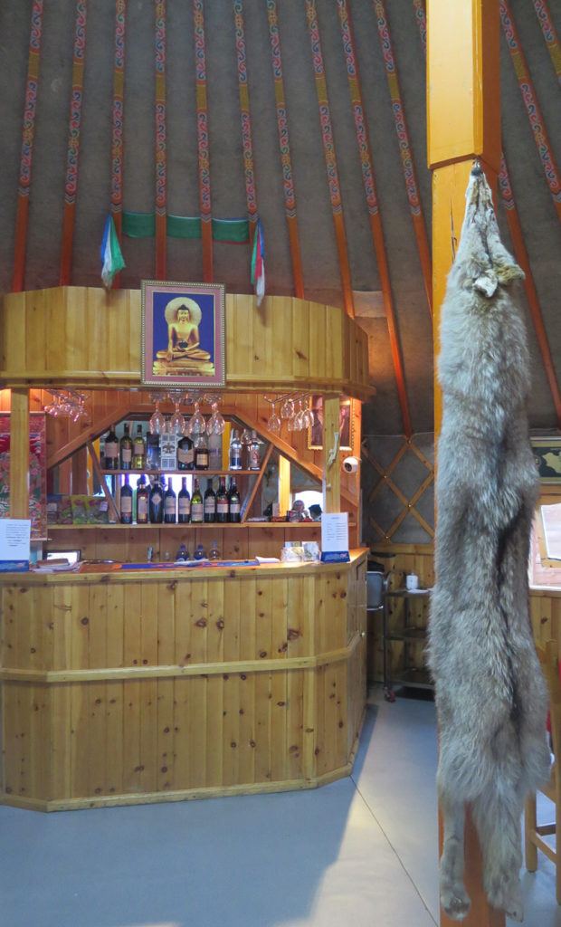 Restaurantjurte mit Wolf an Säule aufgehängt, Blick auf die Bar mit Weingläser